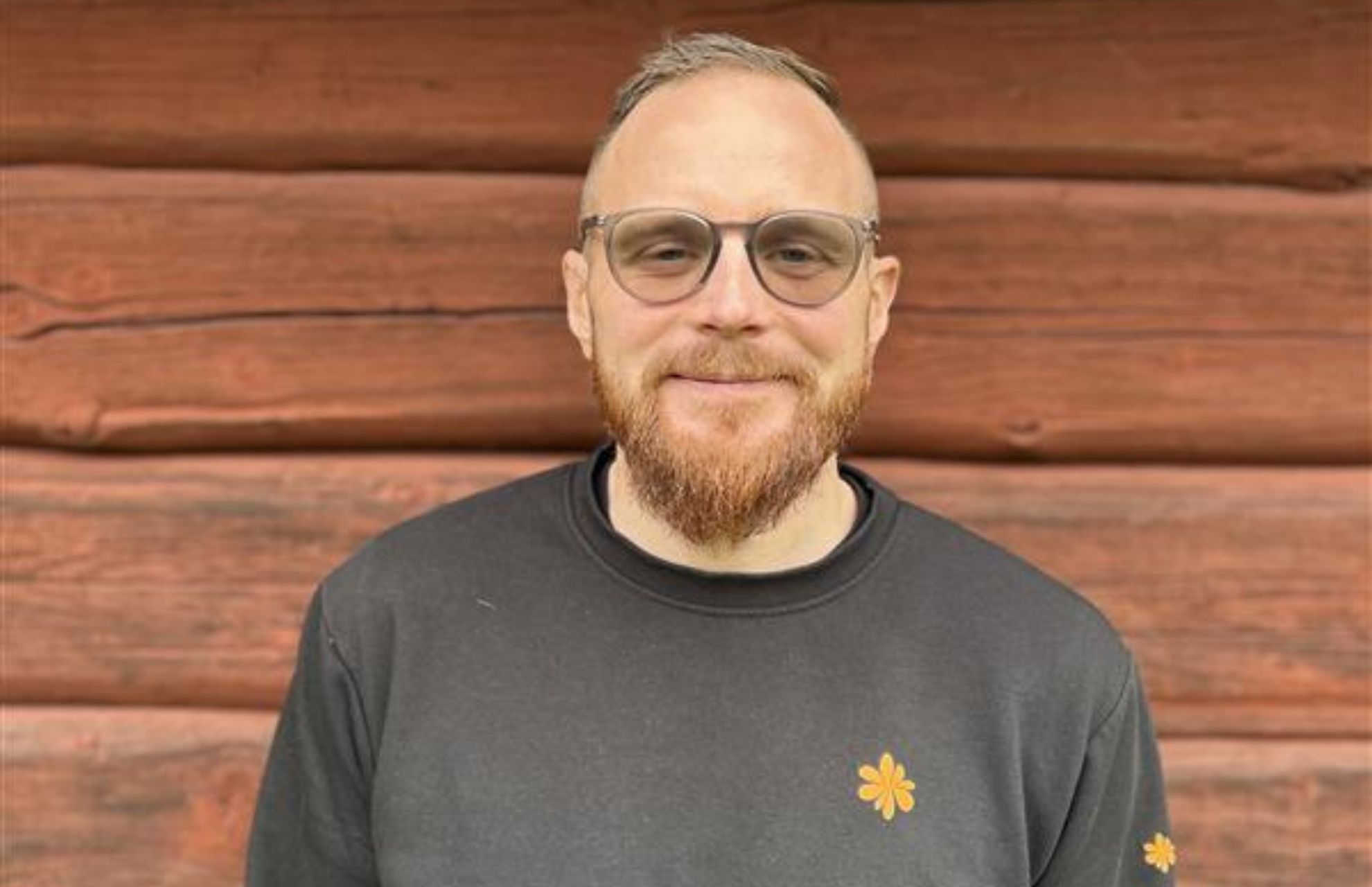 Verksamhetschef Robin Pettersson, leende framför en timmervägg
