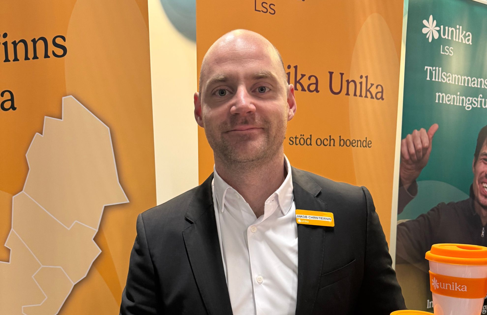 Representant från Unika i mässmiljö, med Unikas monter i bakgrunden