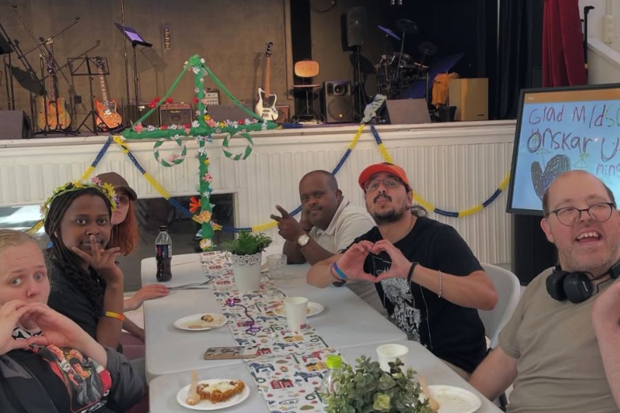 Deltagare p&aring; daglig verksamhet sitter runt ett dukat midsommarbord
